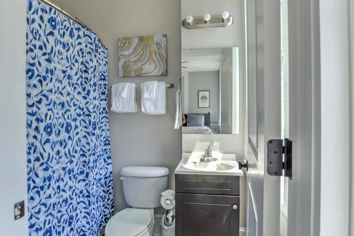 An inviting bathroom with a blue patterned shower curtain, plush white towels, and a modern sink with sleek fixtures. The space feels fresh and spa-like, offering a spot to refresh and rejuvenate after a productive day.