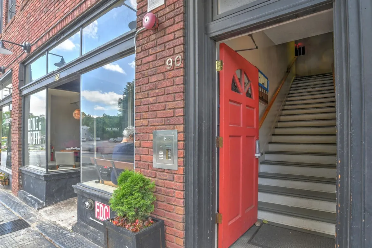 An inviting exterior shot of a red door set in a classic brick wall, with a charming window display. The scene suggests accessibility to local cafés, shops, and a welcoming neighborhood vibe—perfect for families venturing out from their stay.