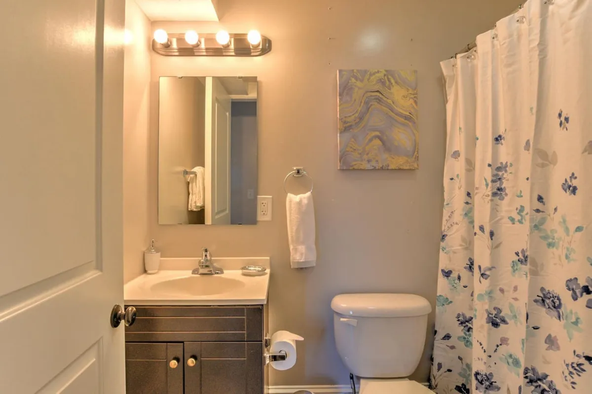 A modern bathroom scene with a stylish vanity, large mirror, and a floral shower curtain. Soft morning light streams through the window, creating a serene and inviting environment ideal for either starting the day with energy or winding down in the evening.